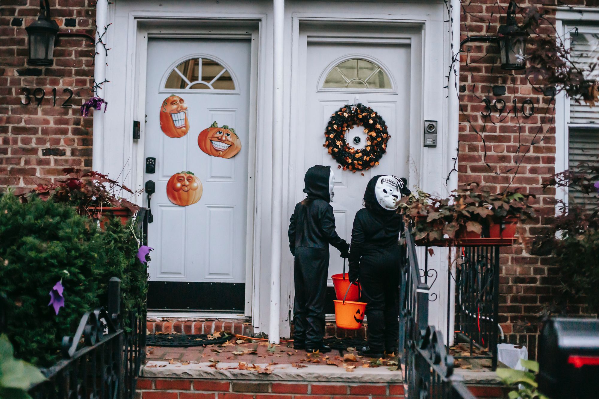 Two trick-or-treaters knocking on a neighbor's door
